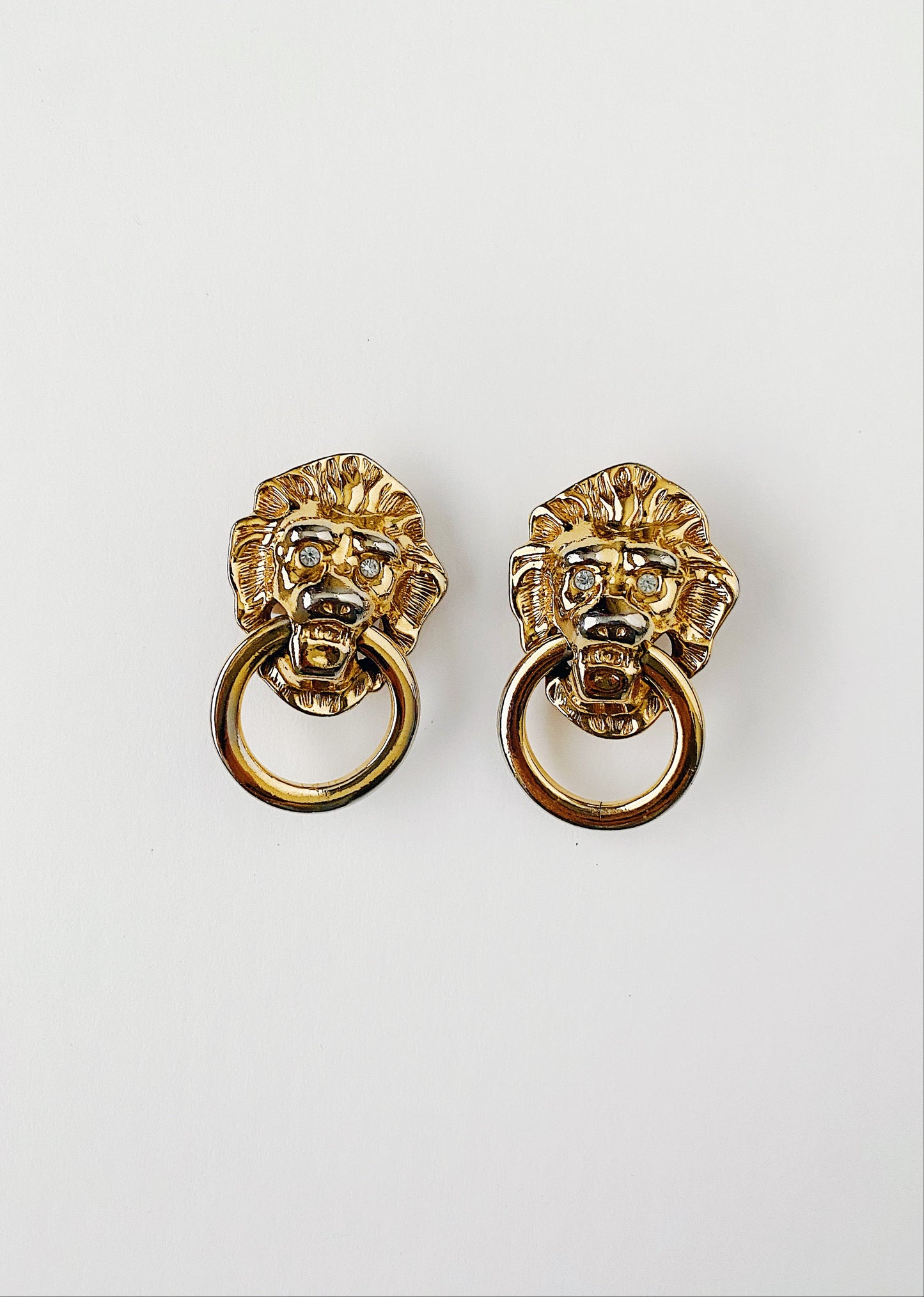 Vintage 1980s KJL for AVON gold-plated lion door knocker clip-on earrings with clear crystal eyes. Bold runway statement jewelry by Kenneth Jay Lane.