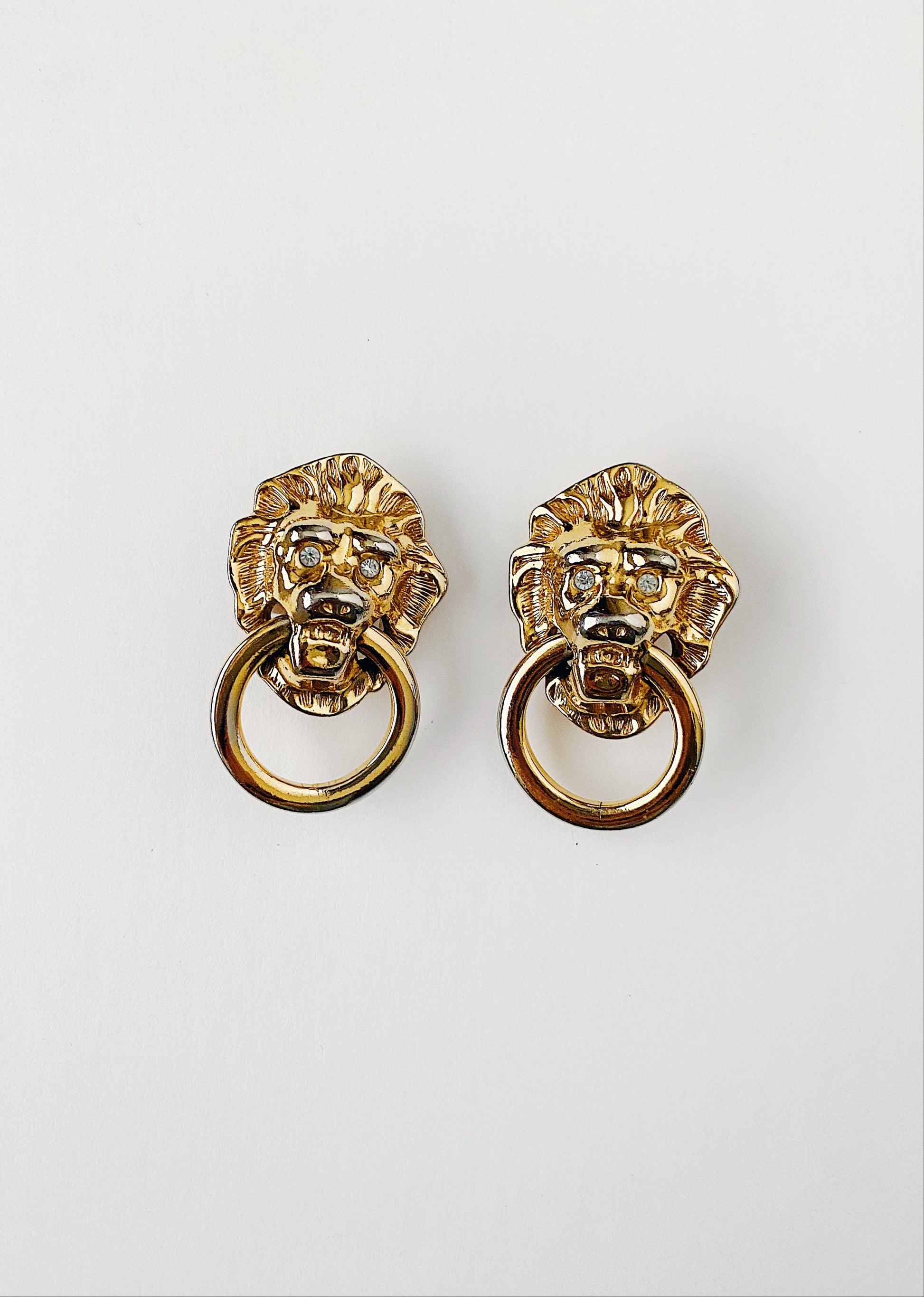 Vintage 1980s KJL for AVON gold-plated lion door knocker clip-on earrings with clear crystal eyes. Bold runway statement jewelry by Kenneth Jay Lane.