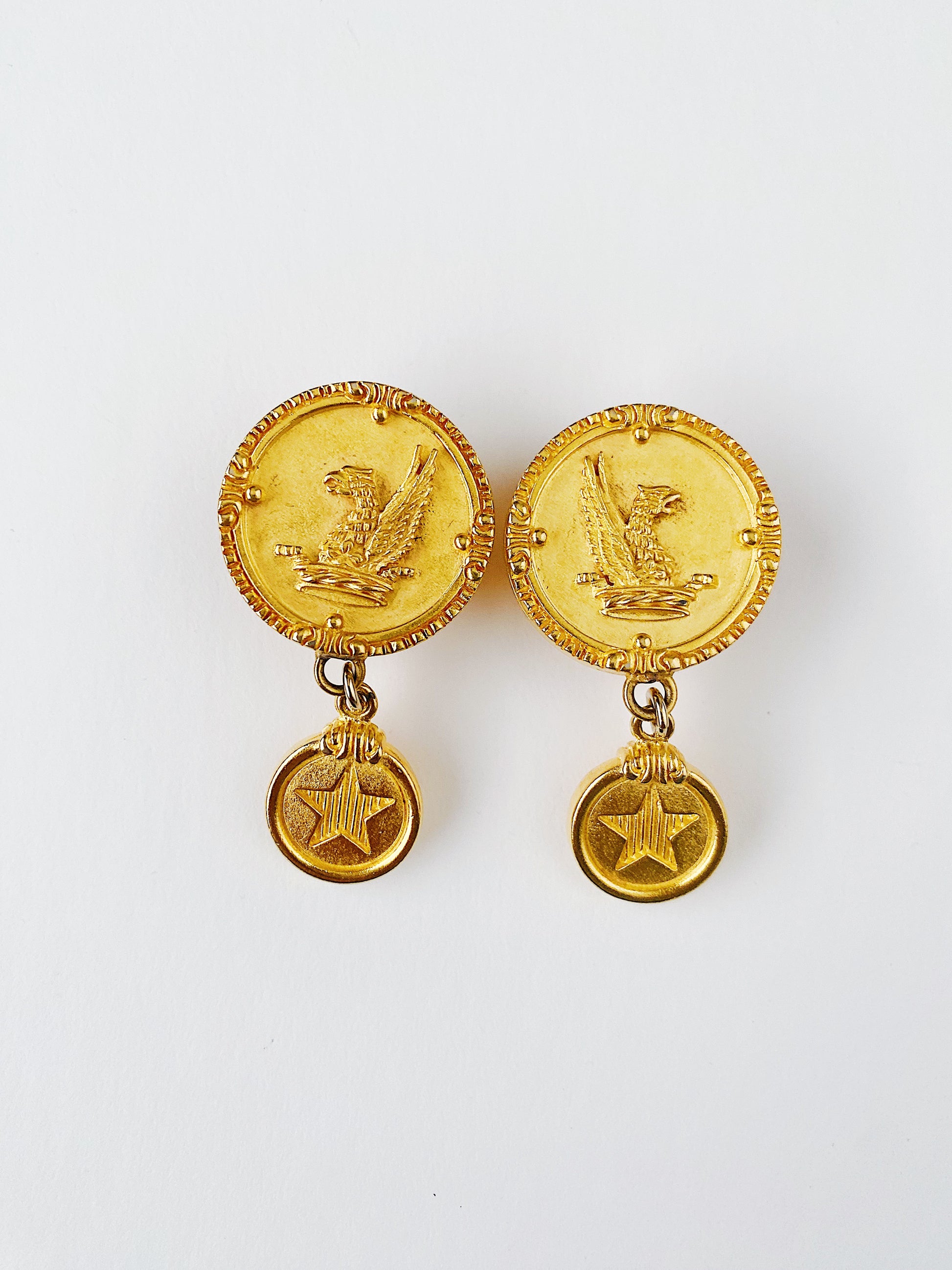 Vintage 1980s Mish Tworkowski Griffin Coin earrings in brushed 18K gold plate with star medallion dangles. Clip-on statement earrings with celestial and mythological motifs.