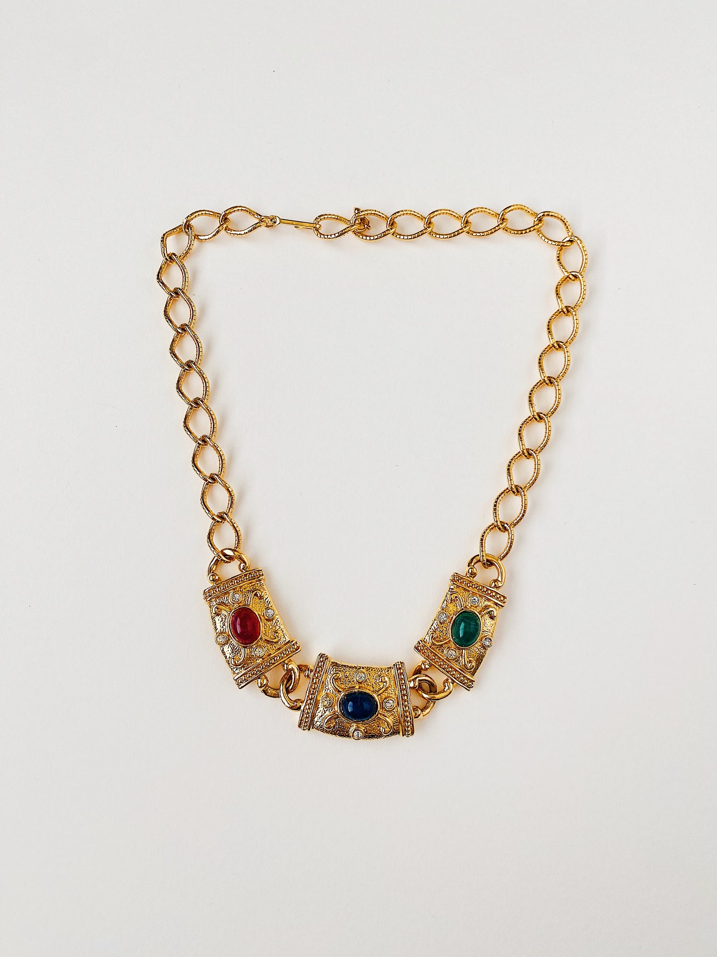 Vintage 1990s AVON signed gold-plated Etruscan Revival statement necklace with textured metalwork, red, green, and blue lucite cabochons, and clear crystal rhinestone accents. Adjustable hook closure.