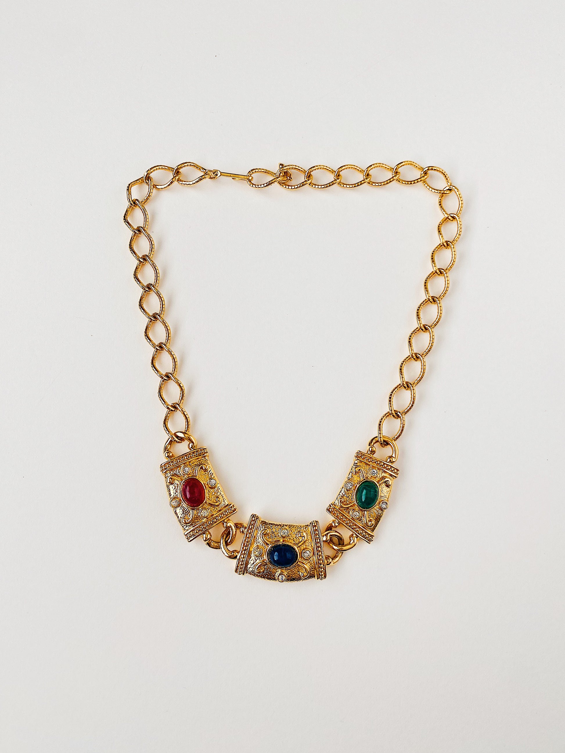 Vintage 1990s AVON signed gold-plated Etruscan Revival statement necklace with textured metalwork, red, green, and blue lucite cabochons, and clear crystal rhinestone accents. Adjustable hook closure.